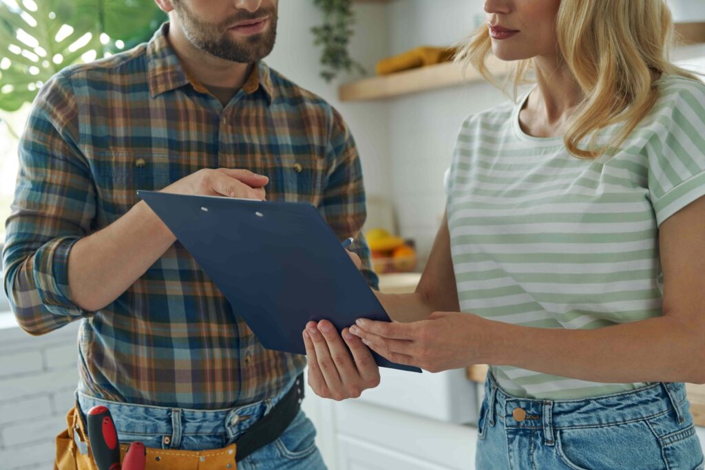 Emergency Plumber Perth Cost: Fixed Pricing Explained 4 Plumber showing a clipboard to a client in the kitchen