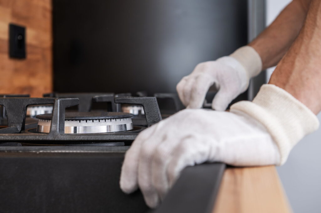 Person in gloves installing  a gas stove burner-Gas Appliance Installation Floreat