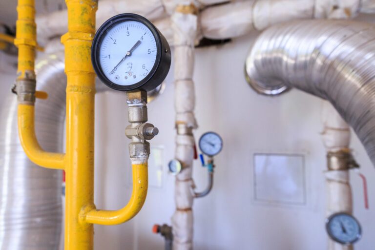 Gas pressure gauge on yellow gas pipe with nearby water pipes and fittings -Leak Detection Como