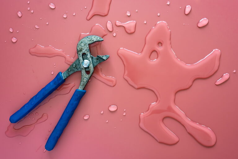 Plumbing pliers beside spilled water illustrating water leak repair 