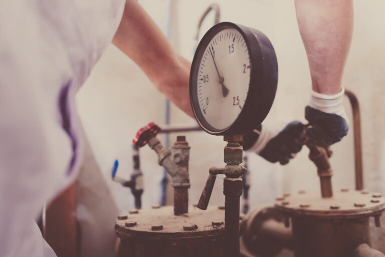Plumber working on backflow prevention system with pressure gauge-Backflow Prevention Burns Beach